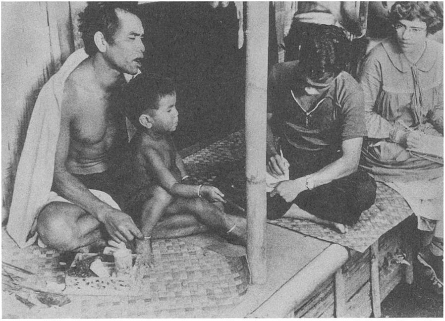 caption = An Ethnographic Interview. Bateson and Mead's Balinese secretary, I Made Kaler, takes notes during Mead's talk with Nang Karma and his son, I Gata. Bajoeng Gede, Bali; 1937; Gregory Bateson, photographer